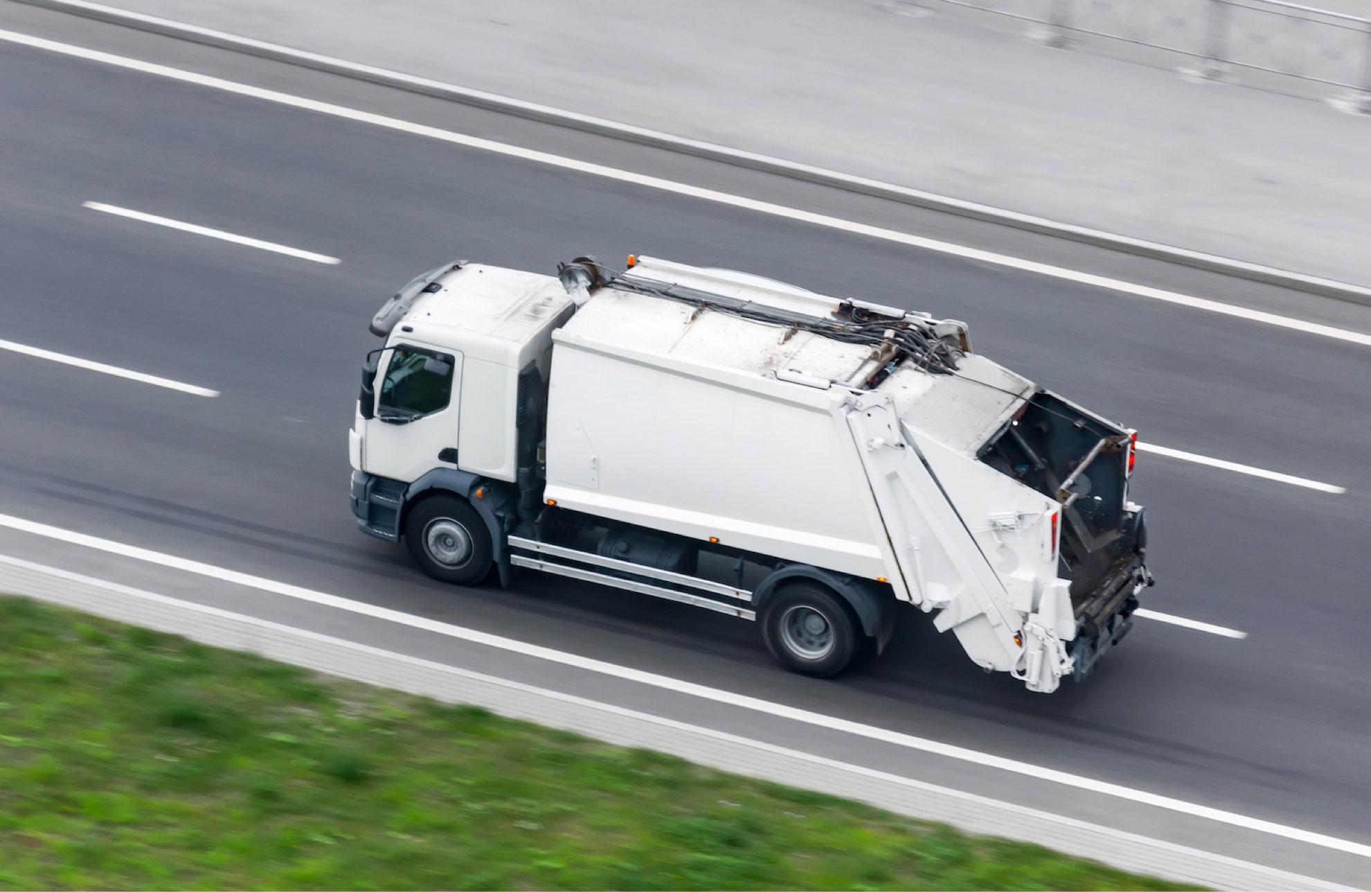 Caminhão compactador em deslocamento por rodovia